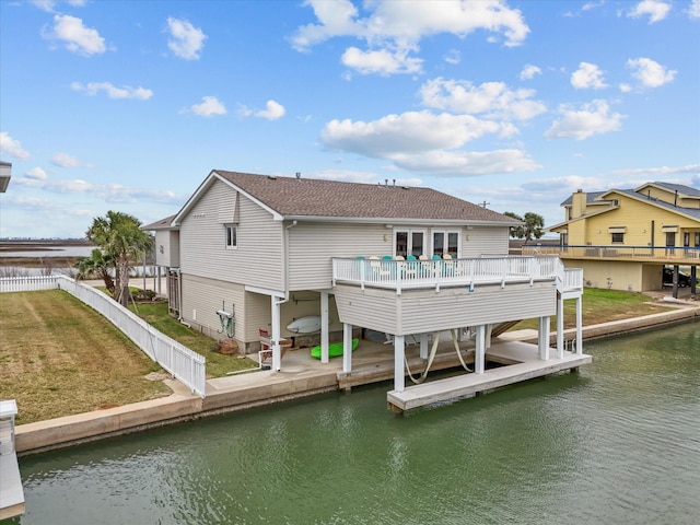 back of property with a yard, a fenced backyard, a deck with water view, and boat lift