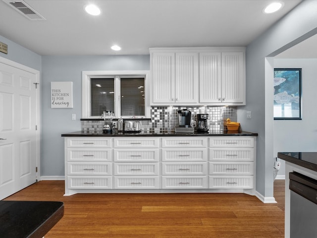 kitchen with stainless steel dishwasher, dark countertops, visible vents, and white cabinetry