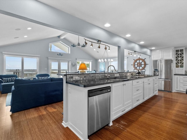 kitchen featuring dark wood-type flooring, open floor plan, lofted ceiling with beams, stainless steel appliances, and a sink