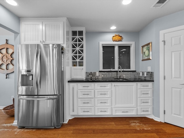 kitchen featuring visible vents, a sink, dark wood-type flooring, stainless steel fridge, and backsplash