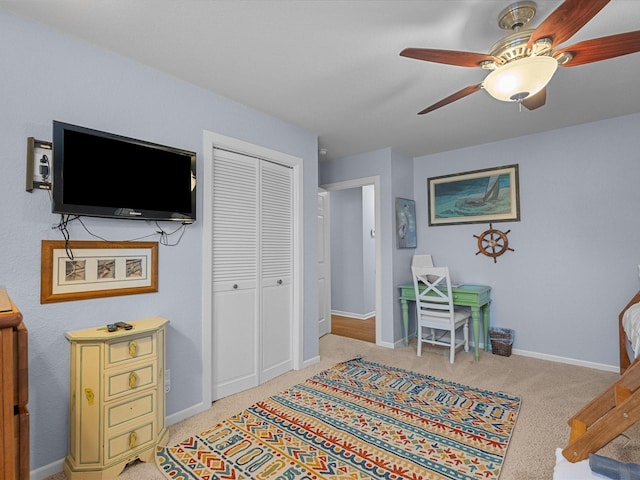 interior space with a closet, light carpet, baseboards, and a ceiling fan