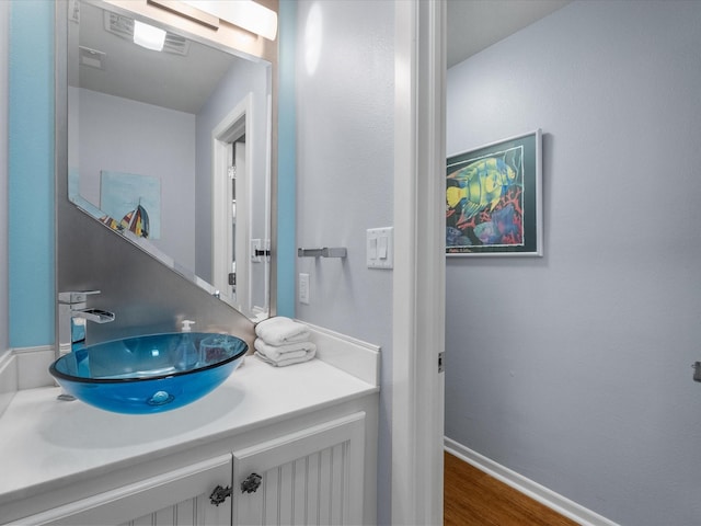 bathroom with vanity, wood finished floors, and baseboards