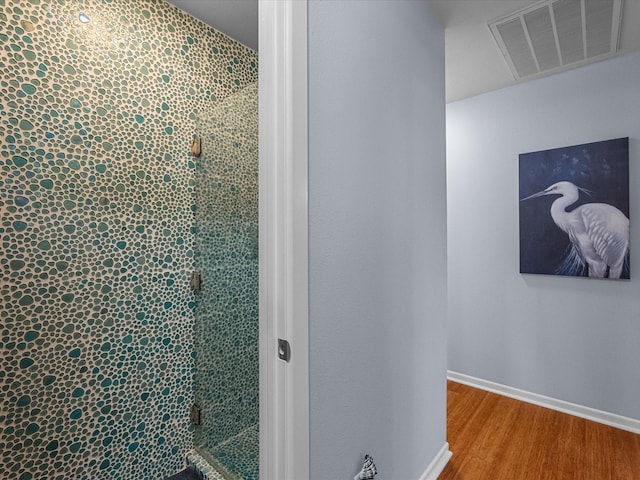 full bath featuring a stall shower, visible vents, baseboards, and wood finished floors