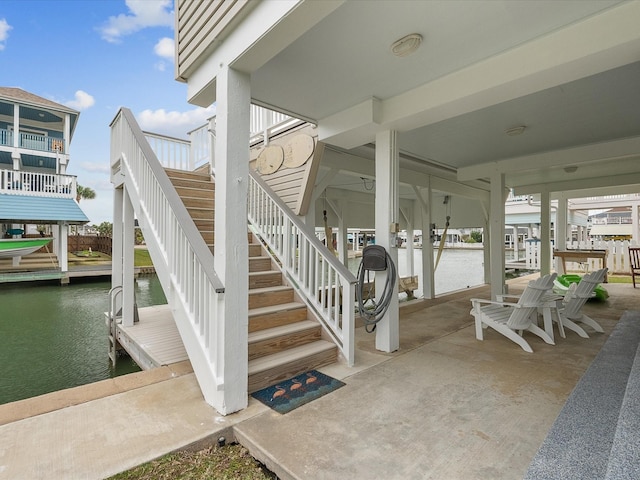 view of patio with stairway, a water view, and a boat dock