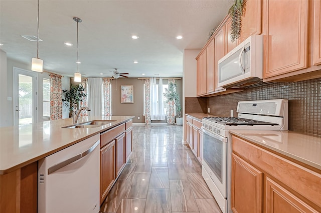 kitchen with visible vents, a sink, plenty of natural light, backsplash, and white appliances