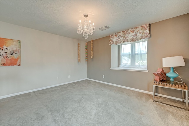 carpeted empty room with visible vents, baseboards, a notable chandelier, and a textured ceiling