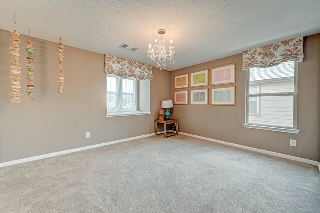 unfurnished room featuring a notable chandelier, visible vents, baseboards, and carpet