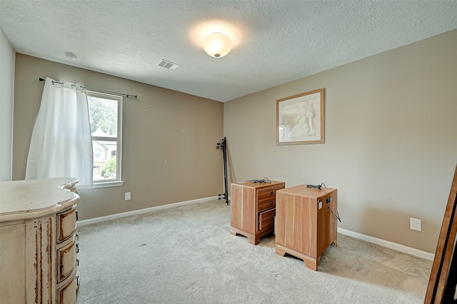 office area with baseboards, light carpet, a textured ceiling, and visible vents