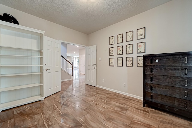 unfurnished bedroom with a textured ceiling and baseboards