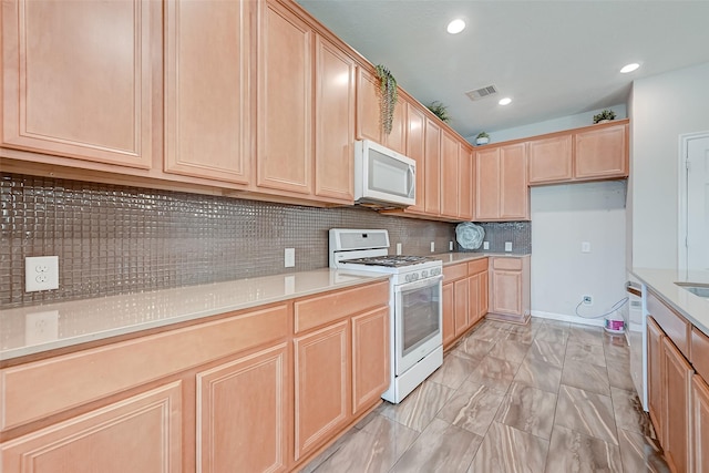 kitchen with white appliances, light brown cabinets, and visible vents