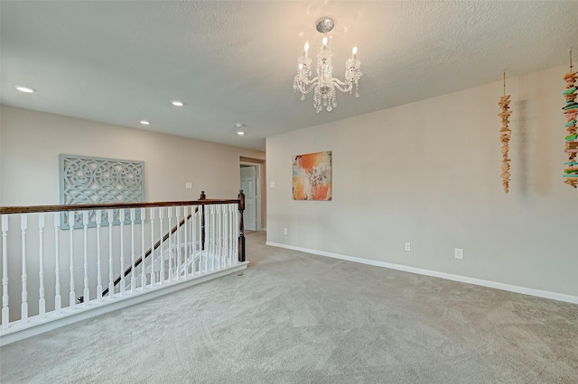 carpeted empty room featuring recessed lighting, baseboards, a textured ceiling, and a chandelier