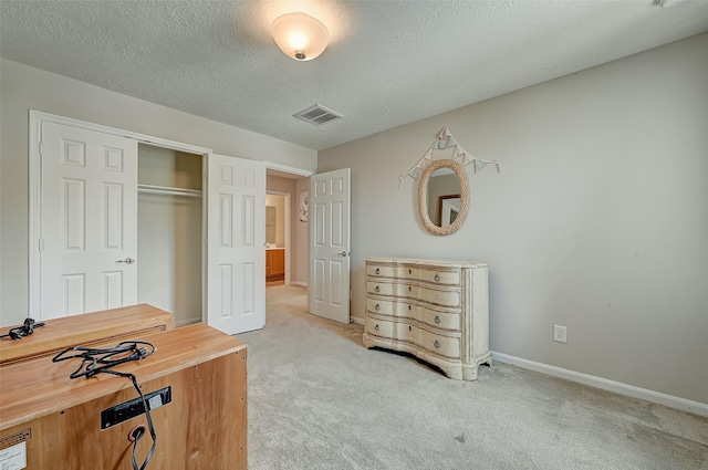 bedroom with baseboards, visible vents, a closet, a textured ceiling, and light carpet