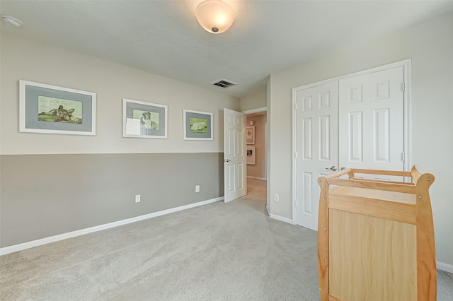 unfurnished bedroom featuring baseboards, visible vents, a closet, and light carpet