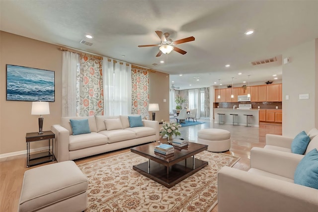 living room featuring light wood-style floors, recessed lighting, visible vents, and baseboards