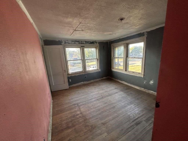 empty room featuring hardwood / wood-style floors, baseboards, and a textured ceiling