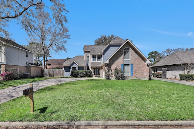 view of front facade featuring a front yard, cooling unit, fence, and brick siding