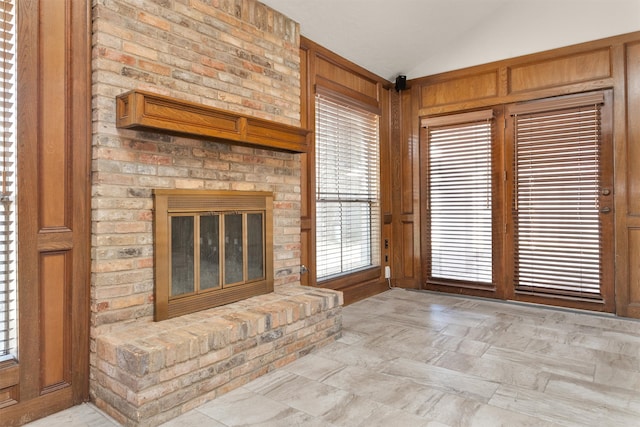 unfurnished living room featuring a brick fireplace and lofted ceiling