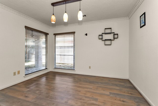 spare room featuring visible vents, ornamental molding, a textured ceiling, wood finished floors, and baseboards