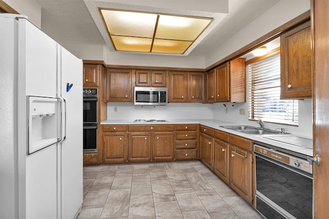 kitchen with brown cabinets, white appliances, and a sink