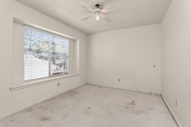 carpeted empty room with baseboards and a ceiling fan