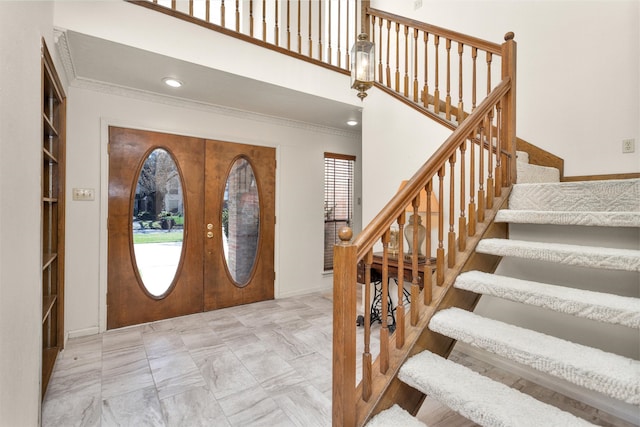 foyer entrance with stairway, french doors, a high ceiling, and ornamental molding