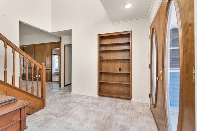 hall featuring built in features, stairs, and baseboards