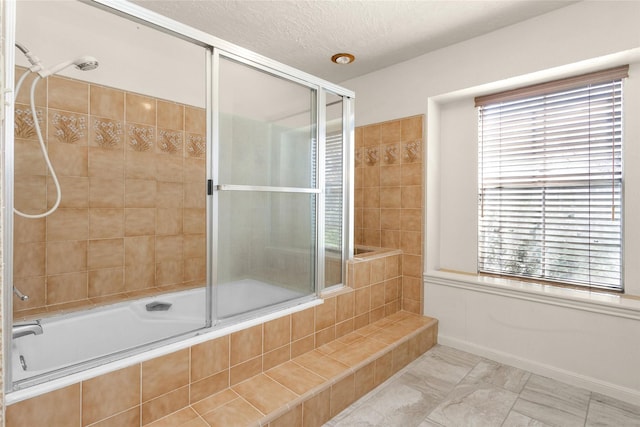 bathroom featuring a textured ceiling, baseboards, and tiled shower / bath combo