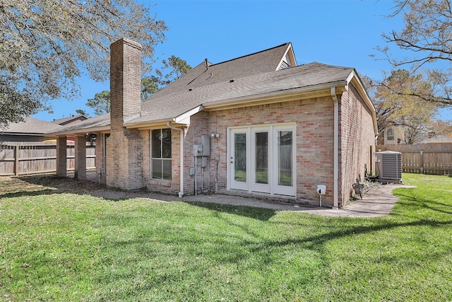 back of house with a lawn, fence, cooling unit, brick siding, and a chimney