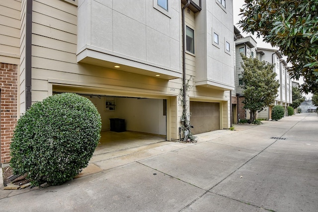 view of home's exterior with an attached garage, brick siding, and driveway