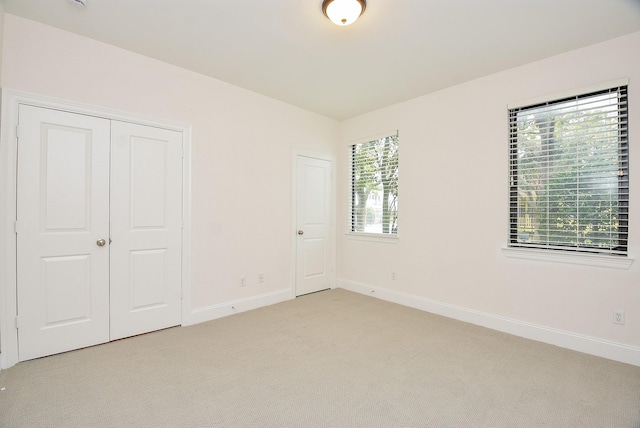 unfurnished bedroom with light colored carpet and baseboards