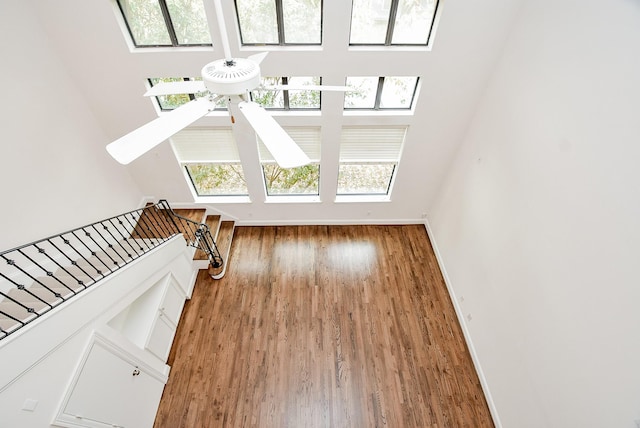 unfurnished living room with a ceiling fan, wood finished floors, and baseboards