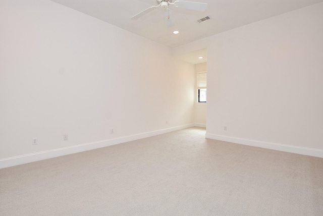 spare room featuring ceiling fan, visible vents, baseboards, and light carpet