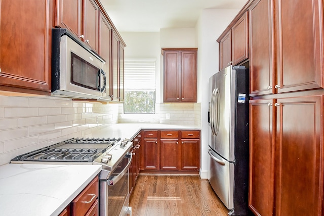 kitchen featuring tasteful backsplash, light wood-type flooring, reddish brown cabinets, and stainless steel appliances