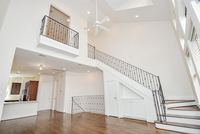 unfurnished living room with stairway, recessed lighting, a high ceiling, wood finished floors, and a ceiling fan