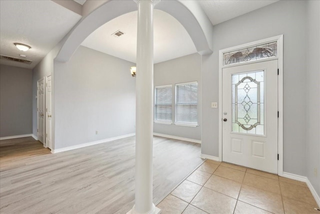 entrance foyer with arched walkways, visible vents, and baseboards