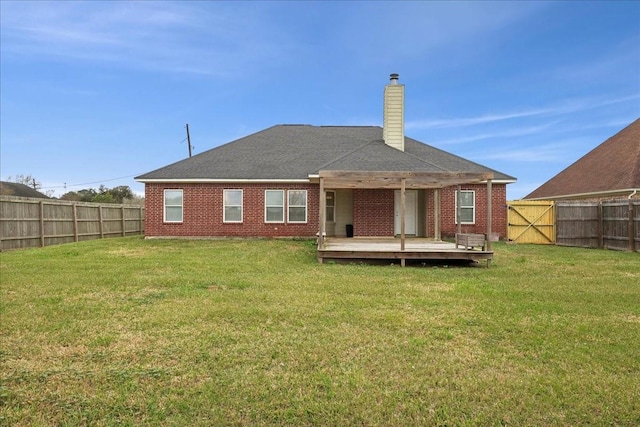 back of property featuring a yard, a fenced backyard, a chimney, and a wooden deck