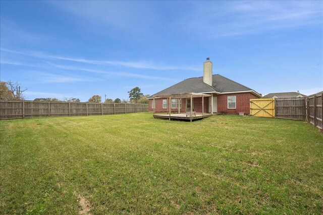 view of yard with a wooden deck, a fenced backyard, and a gate