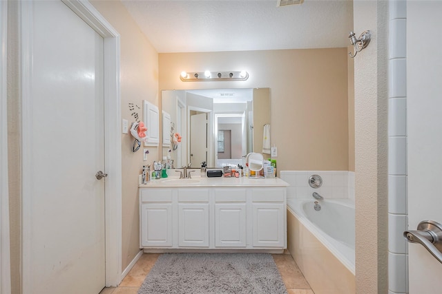 bathroom featuring a garden tub, vanity, and tile patterned flooring