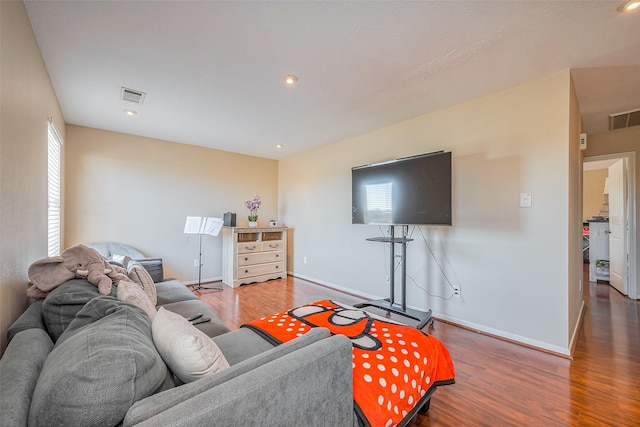 living area with visible vents, baseboards, and wood finished floors