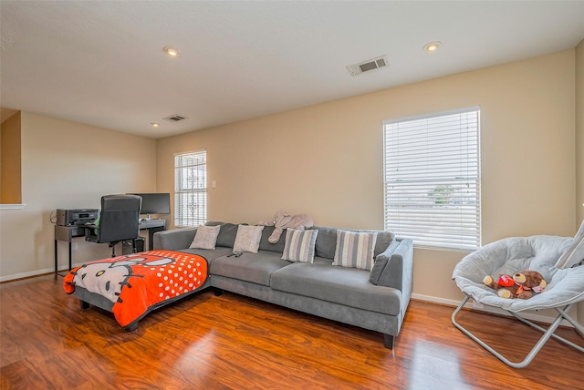 living area with wood finished floors, visible vents, and baseboards