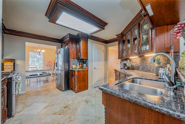 kitchen featuring crown molding, freestanding refrigerator, a notable chandelier, gas stove, and a sink