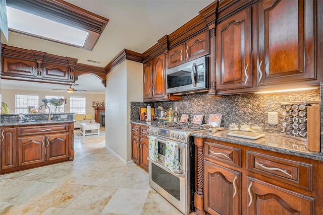 kitchen with dark stone countertops, backsplash, appliances with stainless steel finishes, and ornamental molding