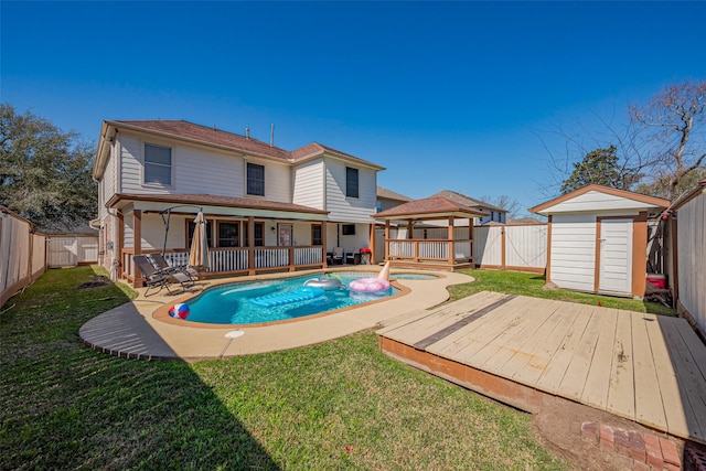 rear view of house featuring a gazebo, a wooden deck, a fenced backyard, and a shed