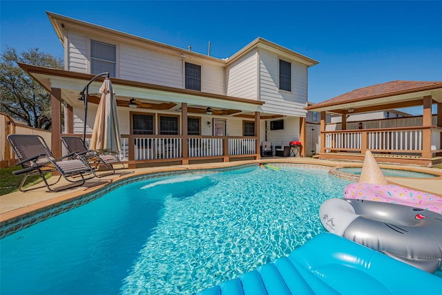 view of swimming pool with fence, a ceiling fan, a fenced in pool, an in ground hot tub, and a patio area