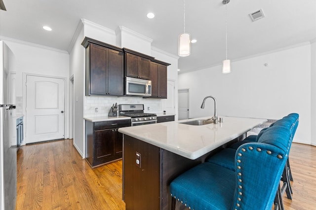 kitchen featuring a kitchen bar, dark brown cabinetry, visible vents, and stainless steel appliances