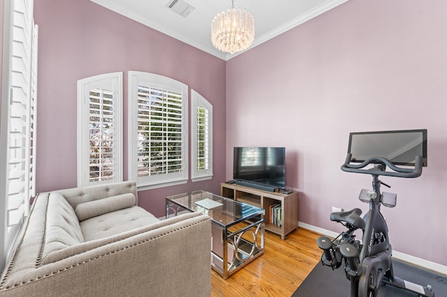 living room with baseboards, visible vents, light wood finished floors, an inviting chandelier, and ornamental molding