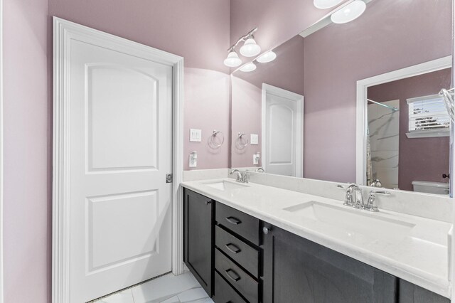 bathroom featuring double vanity, toilet, a shower, and a sink