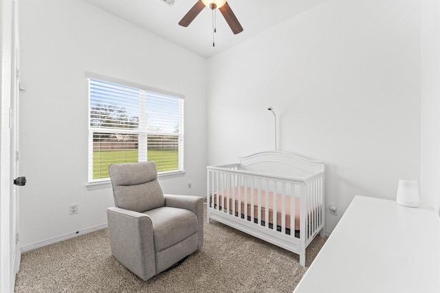 carpeted bedroom featuring baseboards, a nursery area, and ceiling fan