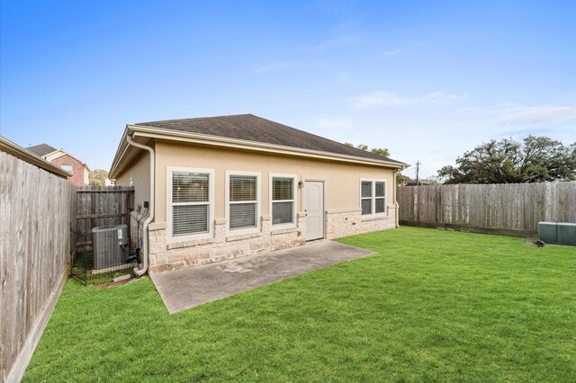 back of property featuring central AC, stucco siding, a fenced backyard, a yard, and stone siding