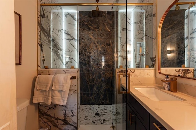 full bath featuring a marble finish shower, toilet, and vanity
